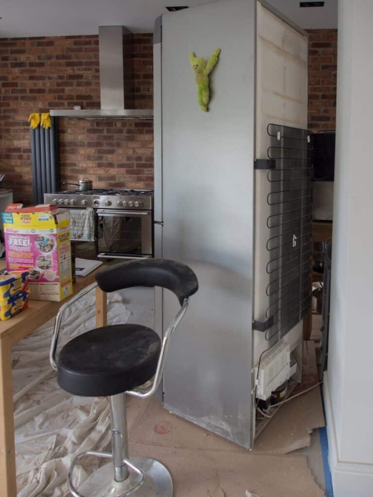 A kitchen with a refrigerator and a chair in it